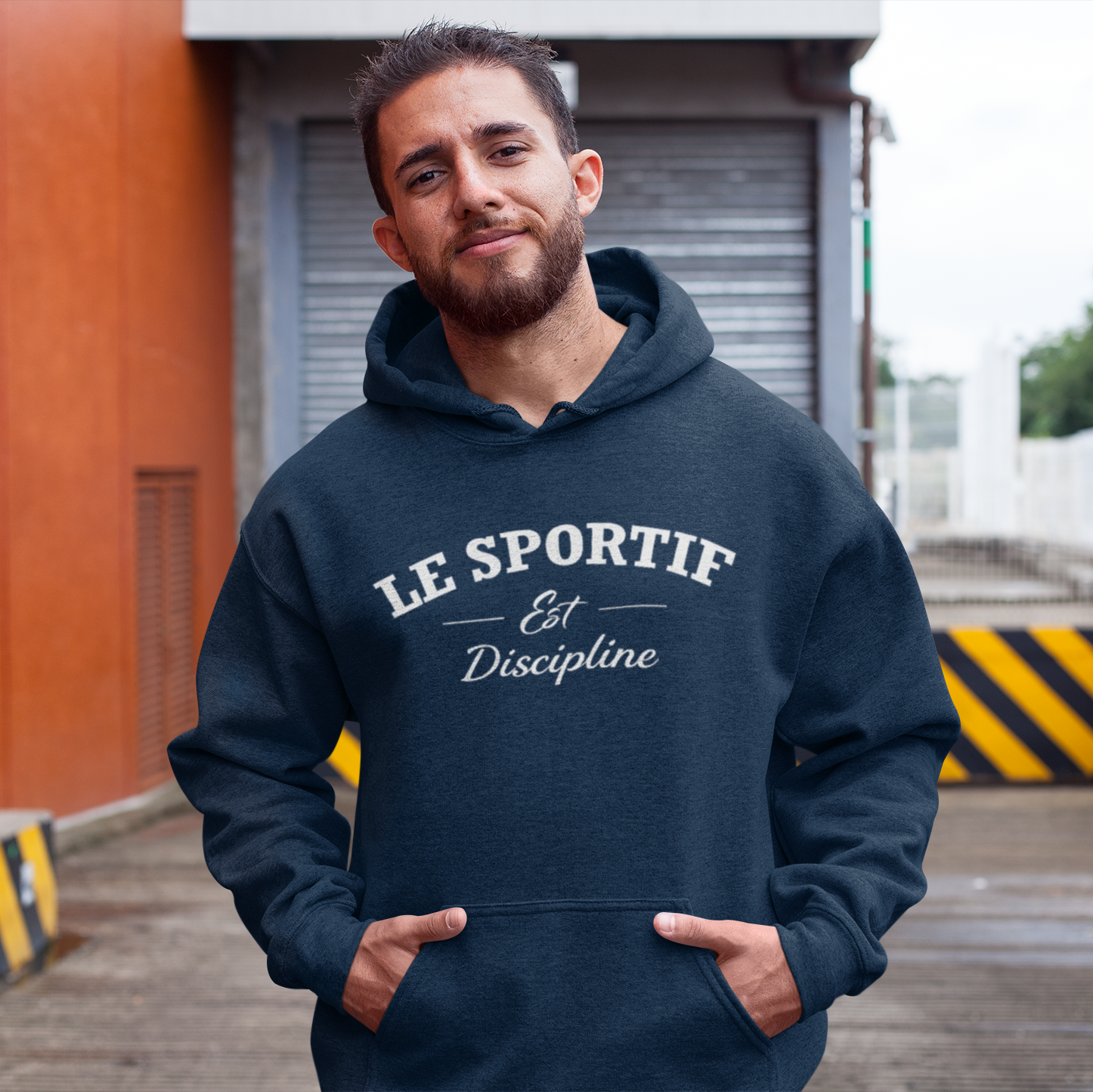 Man wearing a navy hoodie with 'LE SPORTIF Est Discipline' text, standing outdoors.