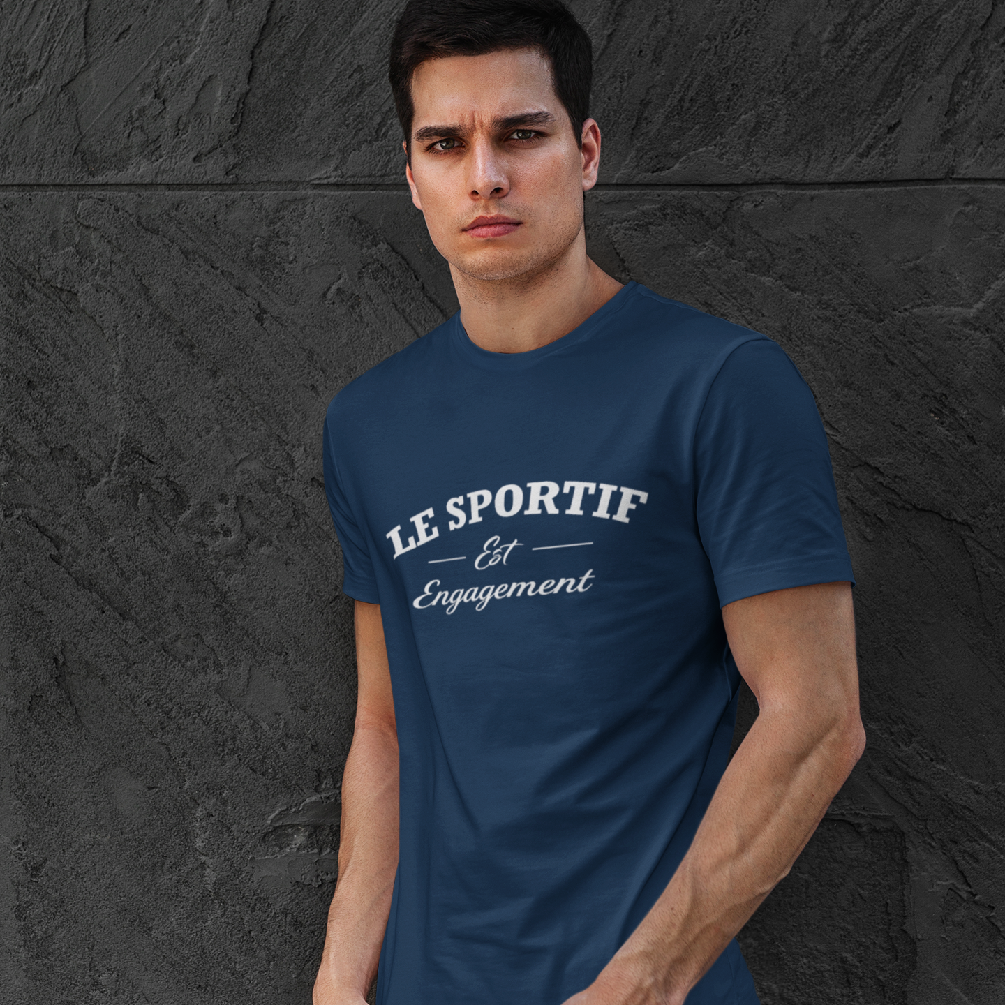 Man wearing a blue t-shirt with text against a dark textured wall