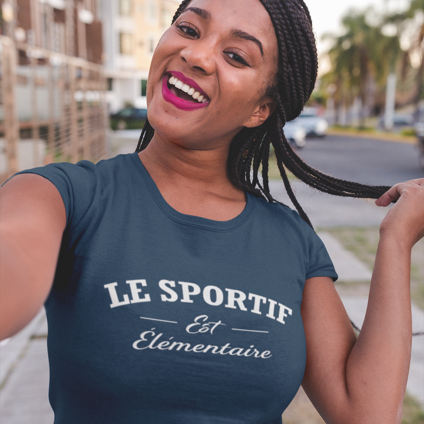Woman wearing a navy blue t-shirt with French text, standing outdoors.